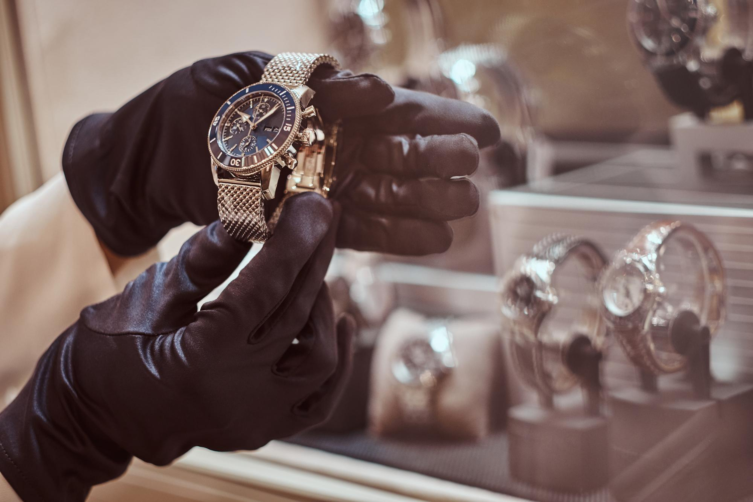 person with black gloves inspecting a standard chronograph watch